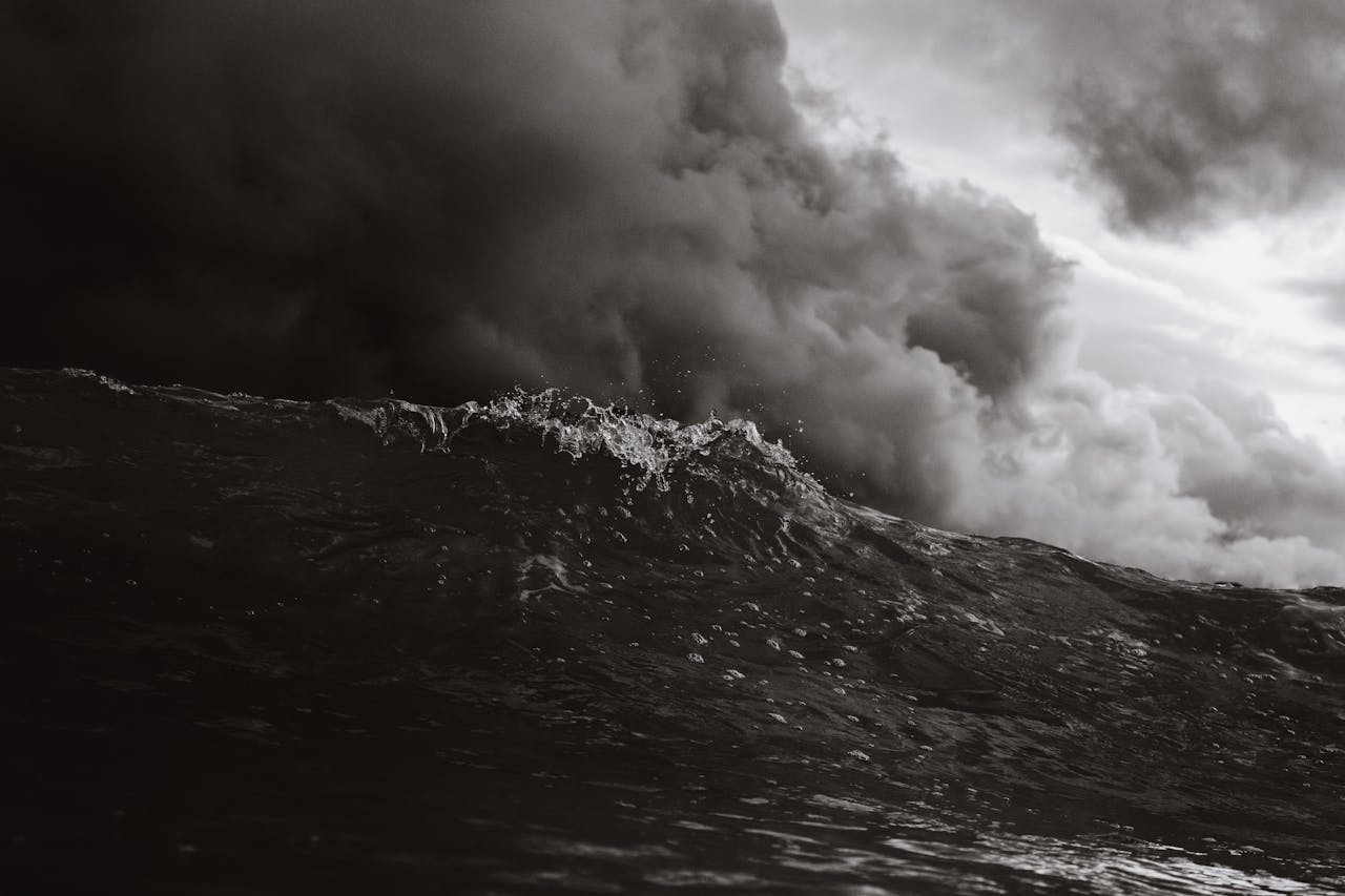 Powerful ocean wave with storm clouds in monochrome, capturing nature's intensity.